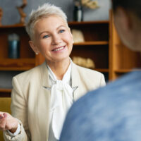 Portrait of experienced stylish human resources woman manager conducting job interview with young female applicant, asking her to tell about work experience, personal qualities and professional skills
